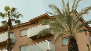Ein mehrstöckiges Gebäude mit Balkonen, Palmen und blauem Himmel.