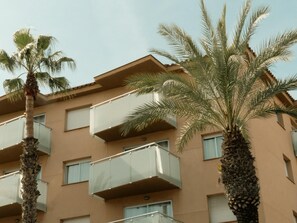 A multi-story building with balconies, palm trees, and a clear sky. - Apartaments Corall 3C with seaview (Salou)