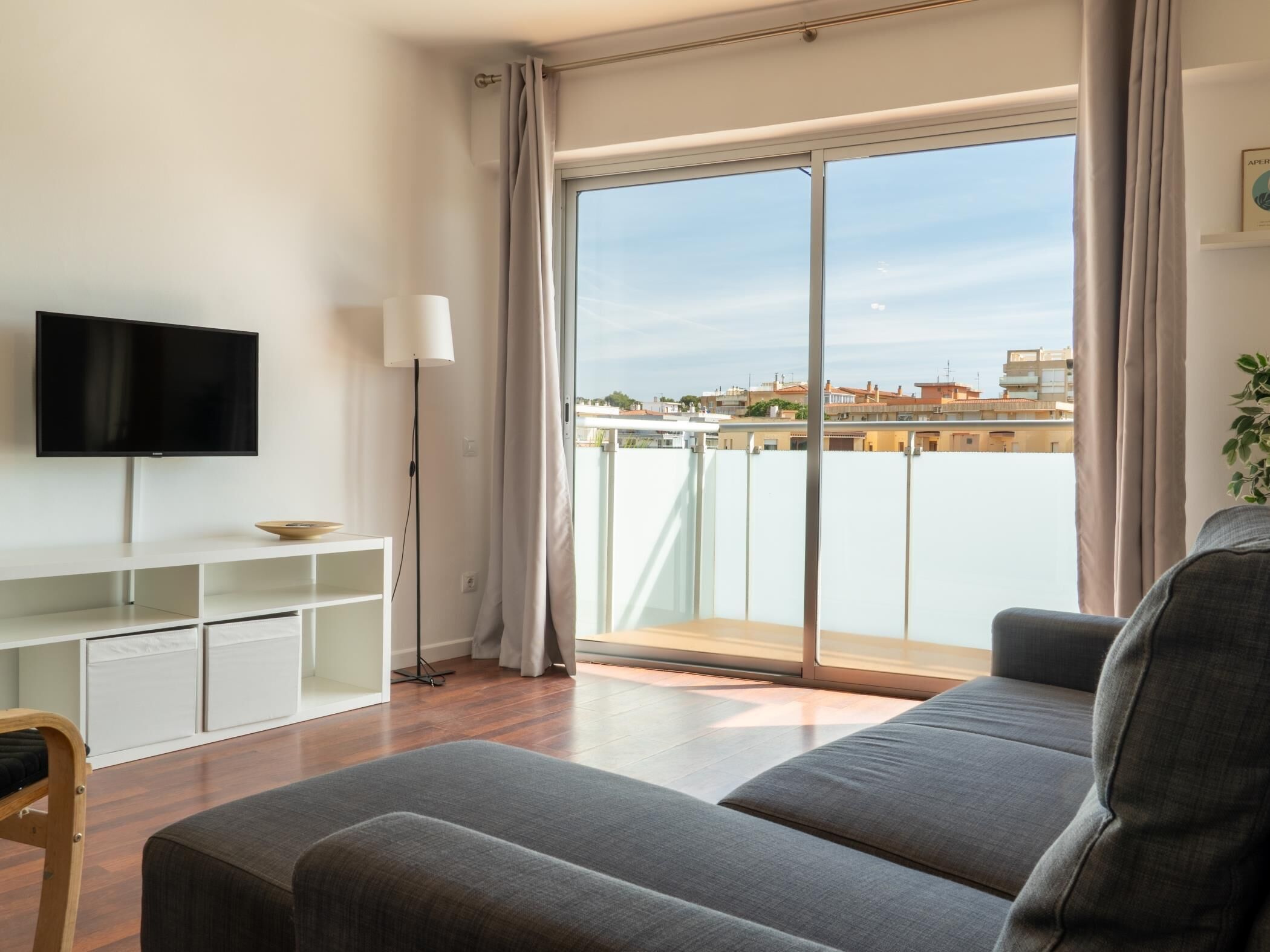 Een moderne woonkamer met een flatscreen televisie, een bank, een kleine tafel en een vloerlamp.