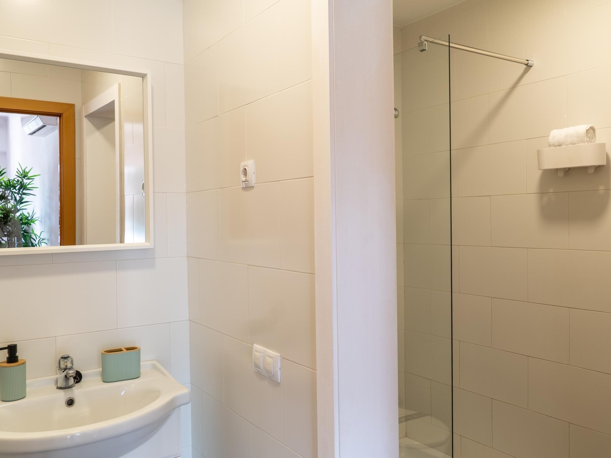 A bathroom with a sink, mirror, and glass shower enclosure.