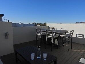An outdoor patio with a table and chairs, a small table with two glasses of water, and a potted plant. - NEW HIGH END LUXURY ARCADIA RETREAT 4BR/4BA PRIVATE ROOFTOP (Phoenix)