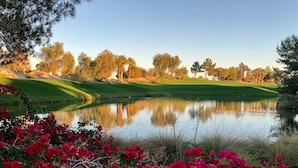 Ein friedlicher Golfplatz mit einem Teich, der Bäume und einen klaren Himmel spiegelt.