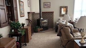 Un salon chaleureux avec une cheminée, un meuble en bois, un canapé et une lampe.