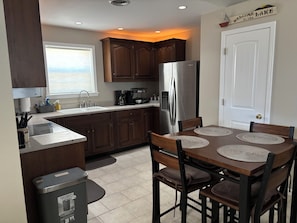 A modern kitchen with dark wood cabinets, a stainless steel refrigerator, and a dining table with placemats.
