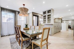 A spacious dining area with a glass-top table, wooden chairs, and a chandelier. - Private Pool Oasis · 5BR House Near The Grove (Beverly Hills)
