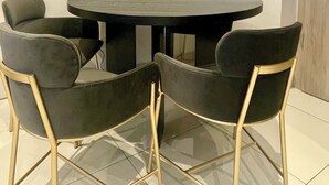 Un comedor con una mesa redonda y cuatro sillas con patas doradas.