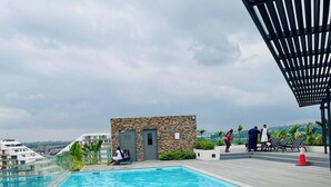 Una piscina con muelle de madera, pared de piedra y un pequeño edificio con puerta.