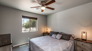 Una camera da letto con un letto, comodini, una ventola a soffitto e una finestra.