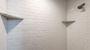 Doccia d'angolo con piastrelle bianche a metro e soffione integrato.