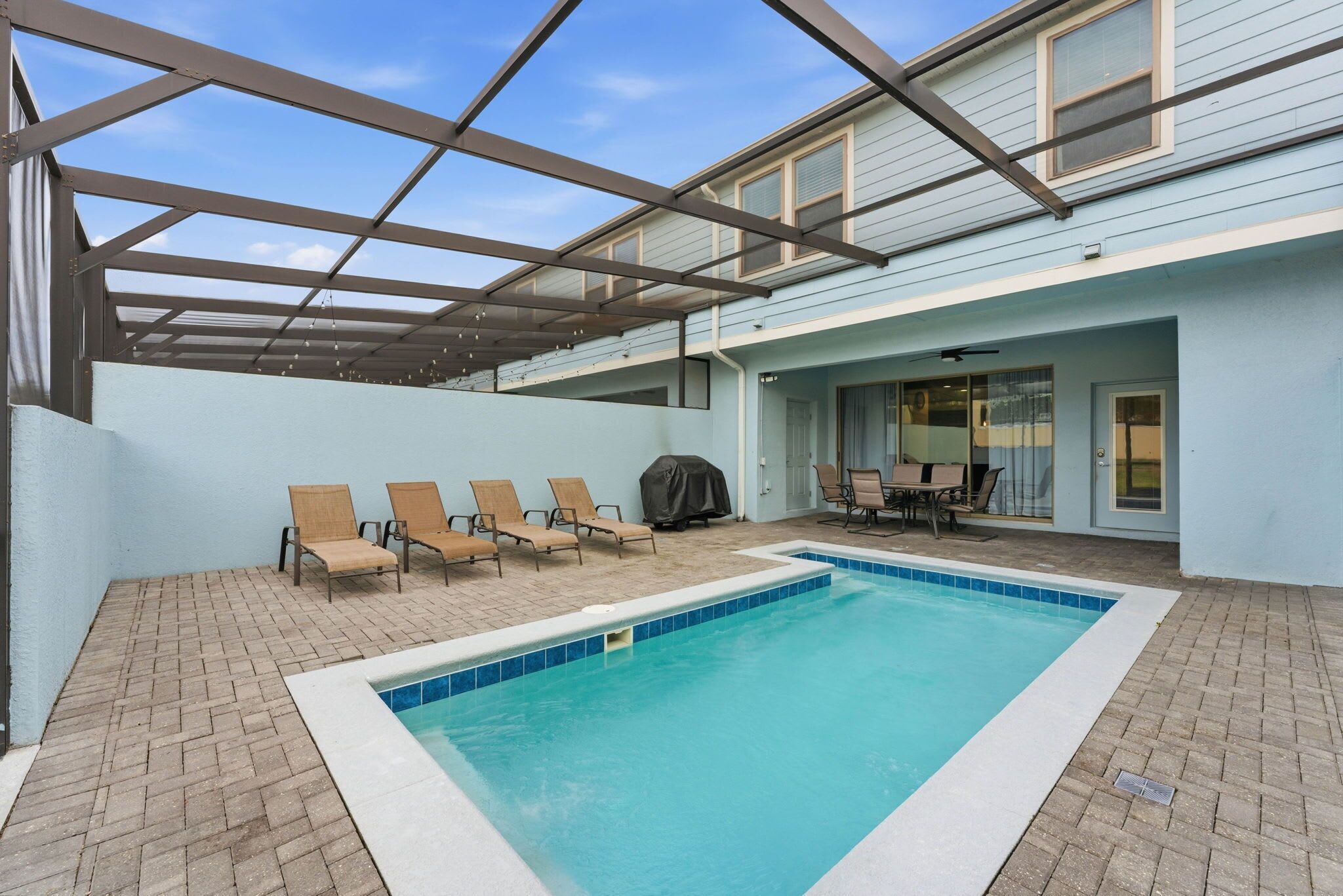 Une piscine extérieure couverte, dotée de chaises longues et d’un barbecue.