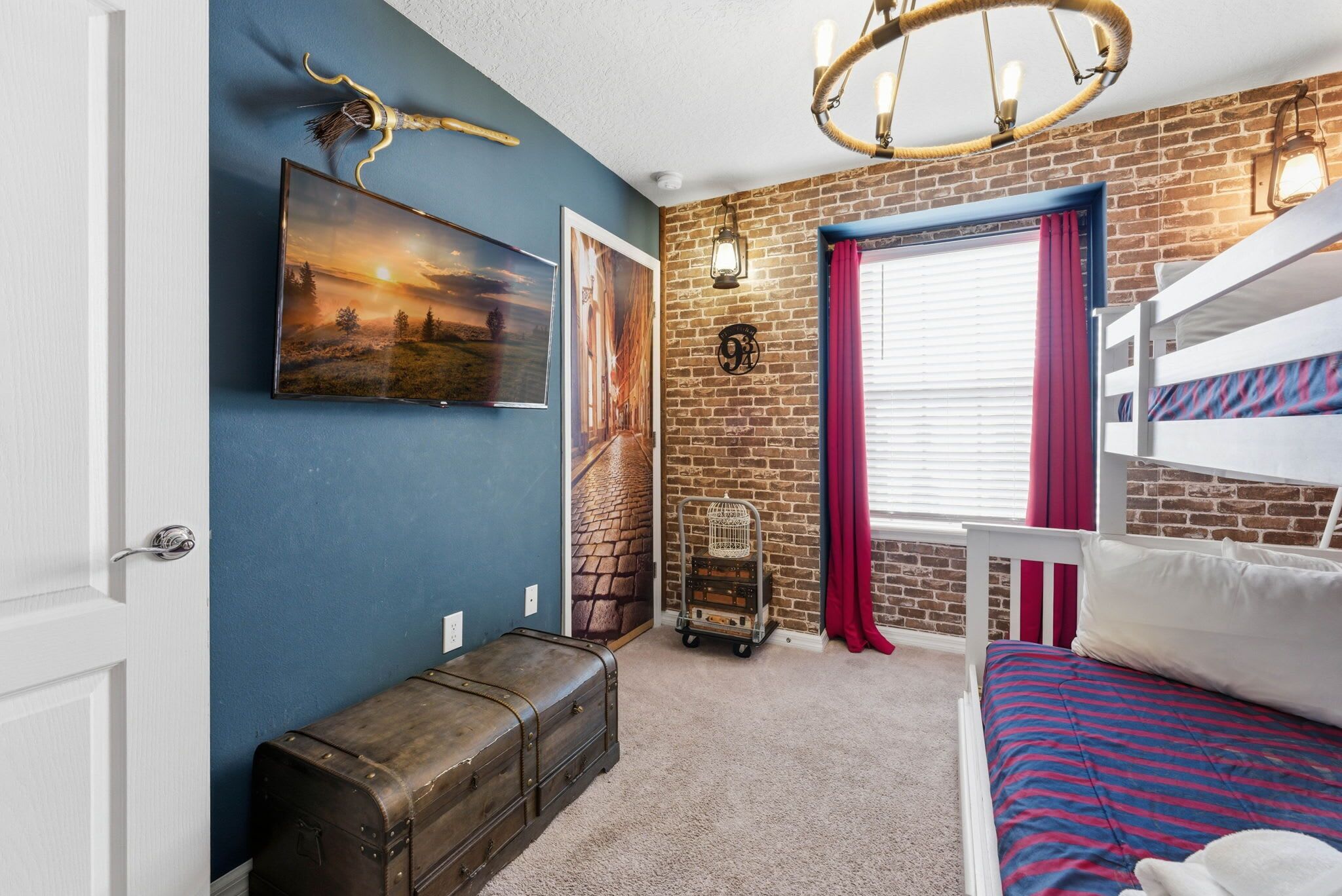 A room with a bunk bed, a suitcase, a wall-mounted lamp, and a framed picture.