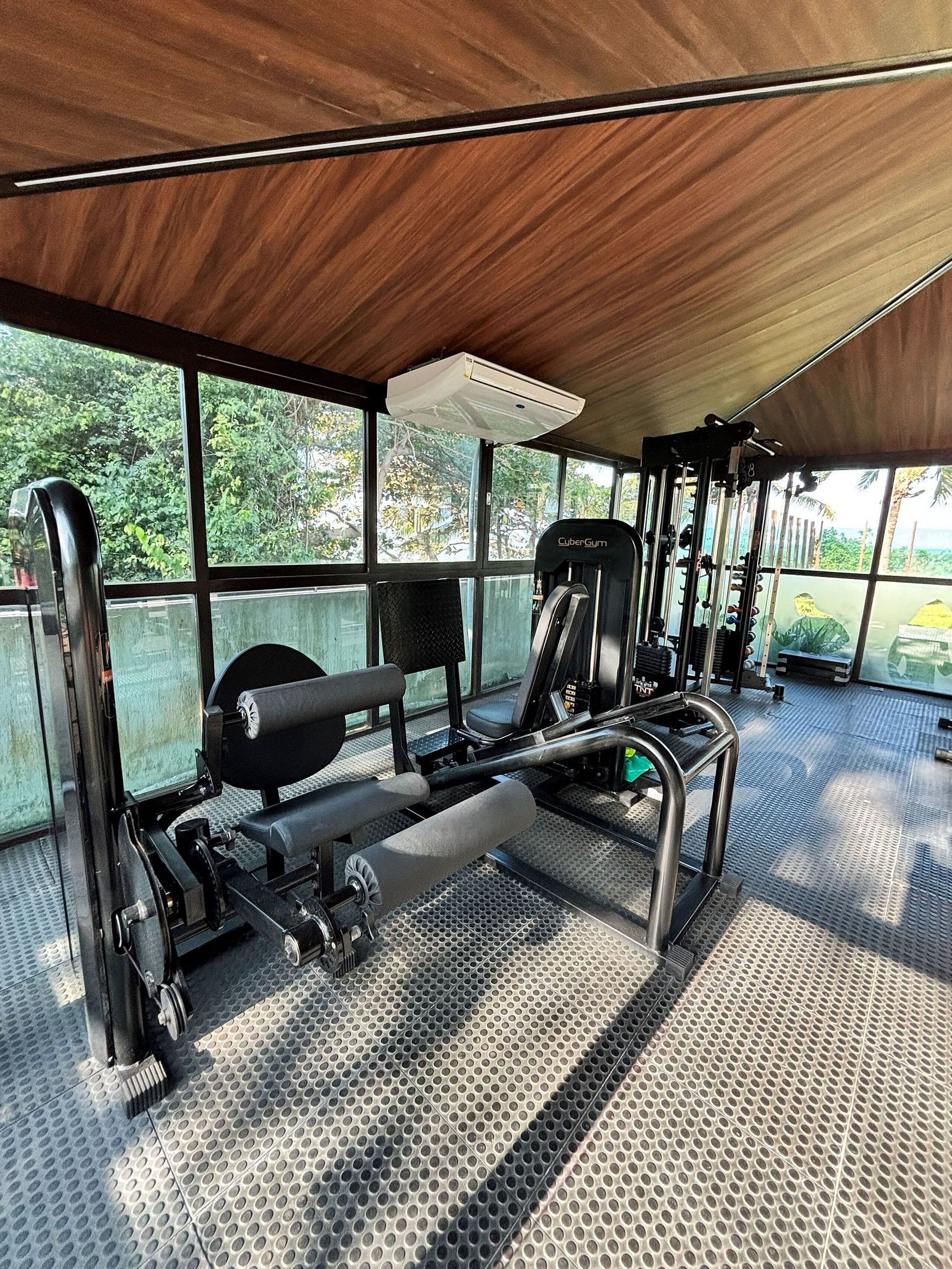 Un gimnasio al aire libre con equipamiento de ejercicio, una zona cubierta y vistas a zonas verdes.