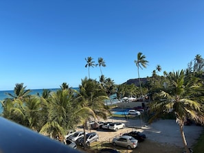 A beachside parking area with cars, palm trees, and a pool. - Flat Gold Vista Mar - Praia de Tabatinga (Conde)