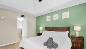 A bedroom with a large bed, two bedside tables with lamps, a wooden headboard, and a green accent wall. - Game Room - Wind Creek Casino- RTJ Golf - 3 Beds - 2 Bath (Wetumpka)