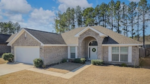 A two-story house with a brick exterior, a garage, and a front porch. - Game Room - Wind Creek Casino- RTJ Golf - 3 Beds - 2 Bath (Wetumpka)