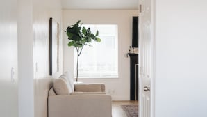 A hallway with a beige sofa, a large plant, and a fireplace. - Spacious 6BR 3BA • Sleeps 16 • Across from Large Park (West Jordan)