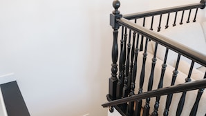 A wooden staircase with black balusters and a white handrail. - Spacious 6BR 3BA • Sleeps 16 • Across from Large Park (West Jordan)