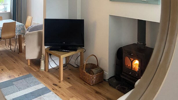 A cozy living room with a television, a fireplace, a dining area with a table and chairs, and a large painting on the wall.