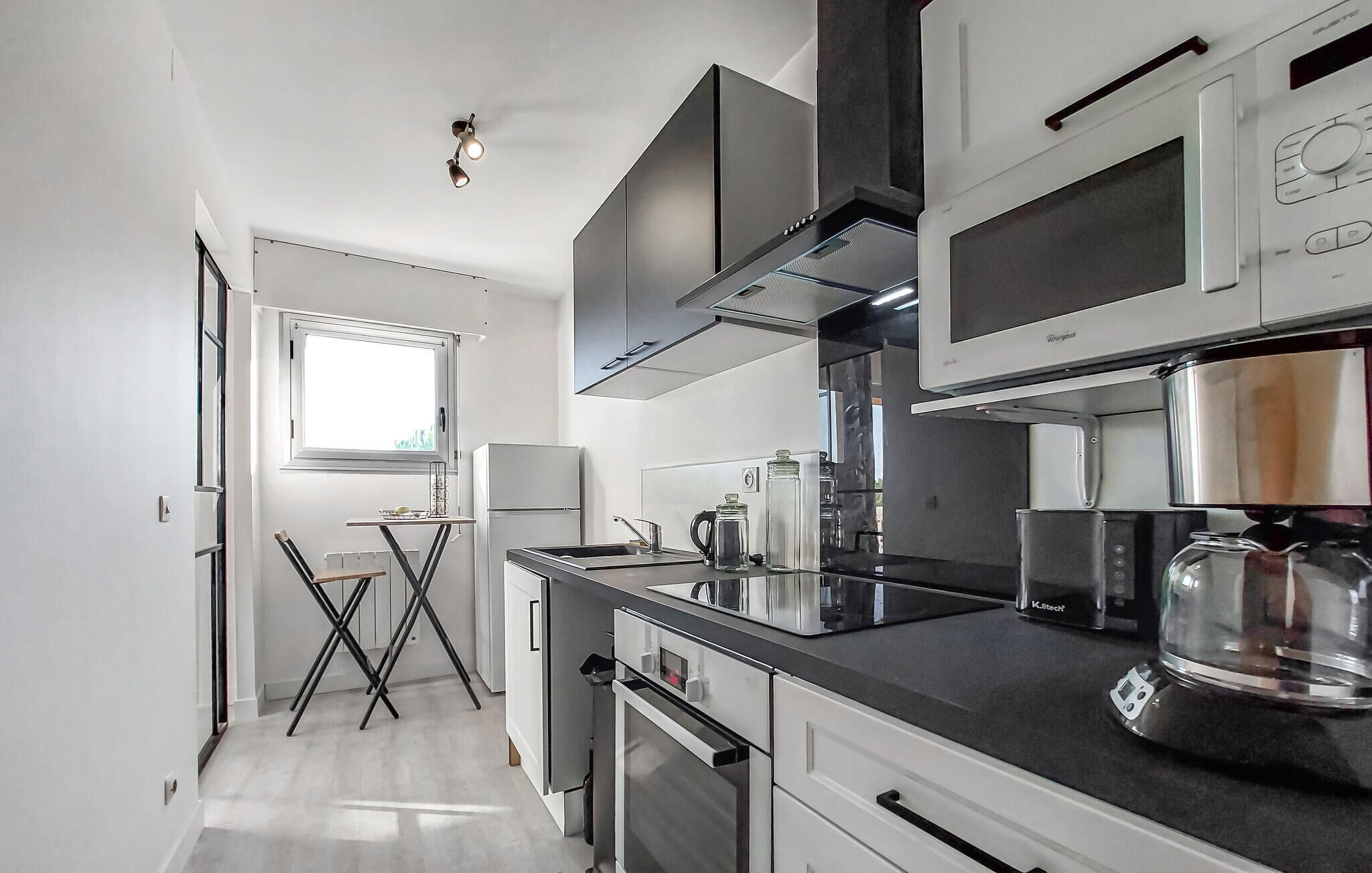 Een moderne keuken met roestvrijstalen apparatuur, een zwart aanrecht en een raam voor natuurlijk licht.