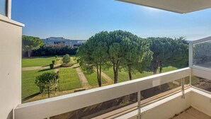 Ein Balkon mit Blick auf einen gepflegten Garten und ein Gebäude in der Ferne.