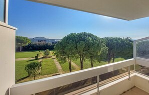 Ein Balkon mit Blick auf einen gepflegten Garten und ein Gebäude in der Ferne.