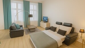 Een moderne hotelkamer met een bed, twee banken, een televisie en een lamp.