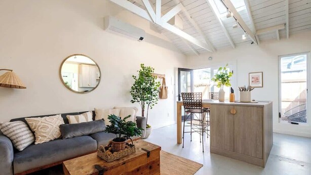 A modern living room with a sofa, coffee table, and a dining area with chairs and a small kitchen counter. - Unique & Cozy Gem: Mins to Beach ~ Patio (San Diego)
