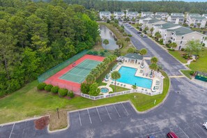 Eine Vogelperspektive auf ein Wohngebiet mit Tennisplatz, Schwimmbad und Parkplatz.
