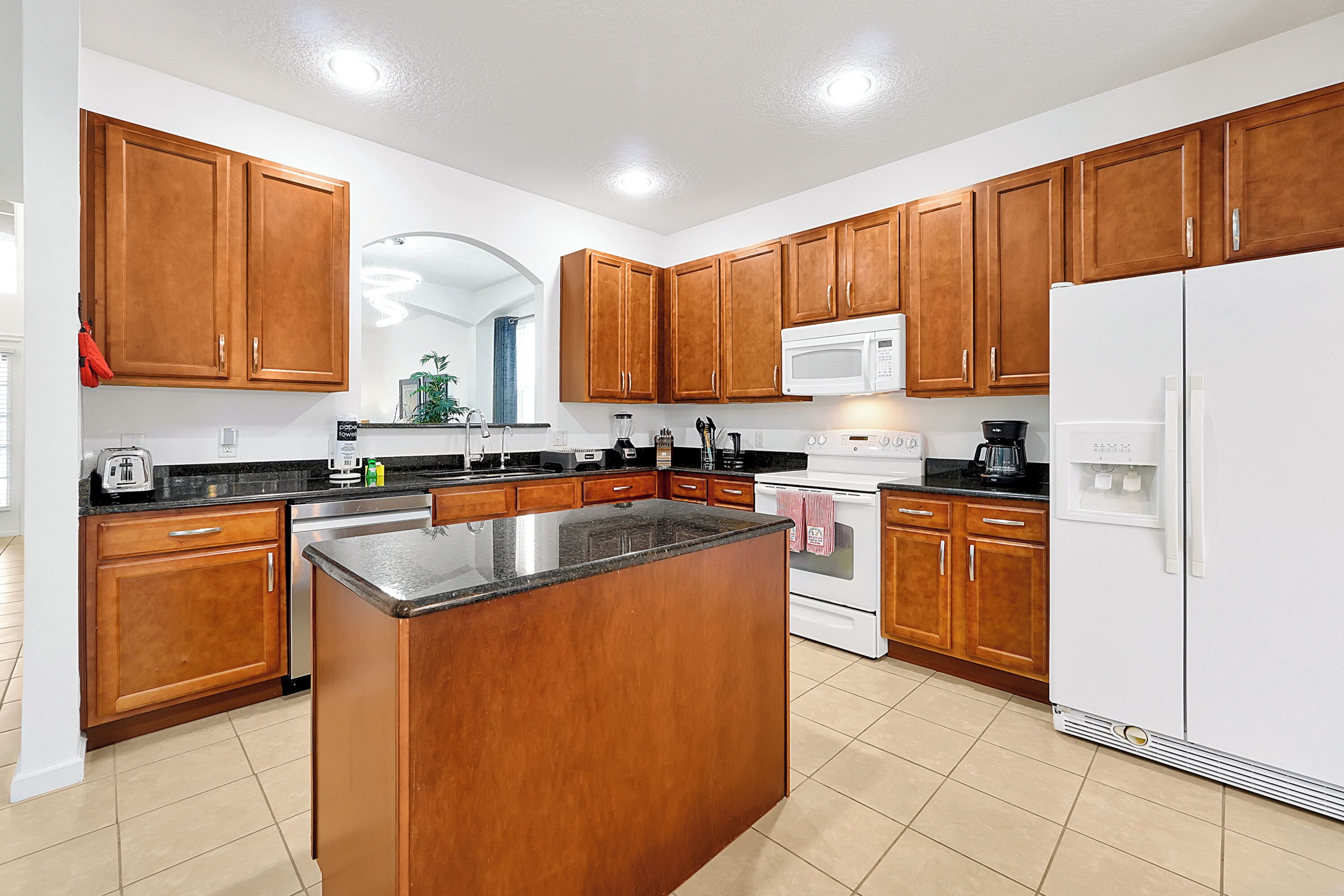 A modern kitchen with wooden cabinets, a central island, a microwave, a stove, and a refrigerator.