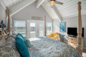 Ein Schlafzimmer mit einem großen Bett, einem Deckenventilator, einem Fernseher und einem Schild mit der Aufschrift 'BEACH HOUSE'.