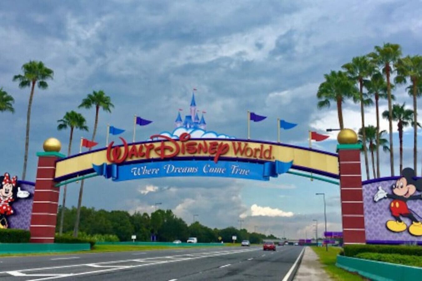 Suuri kyltti, jossa lukee "Walt Disney World" ja "Täällä unelmat toteutuvat", on sijoitettu tien yläpuolelle.