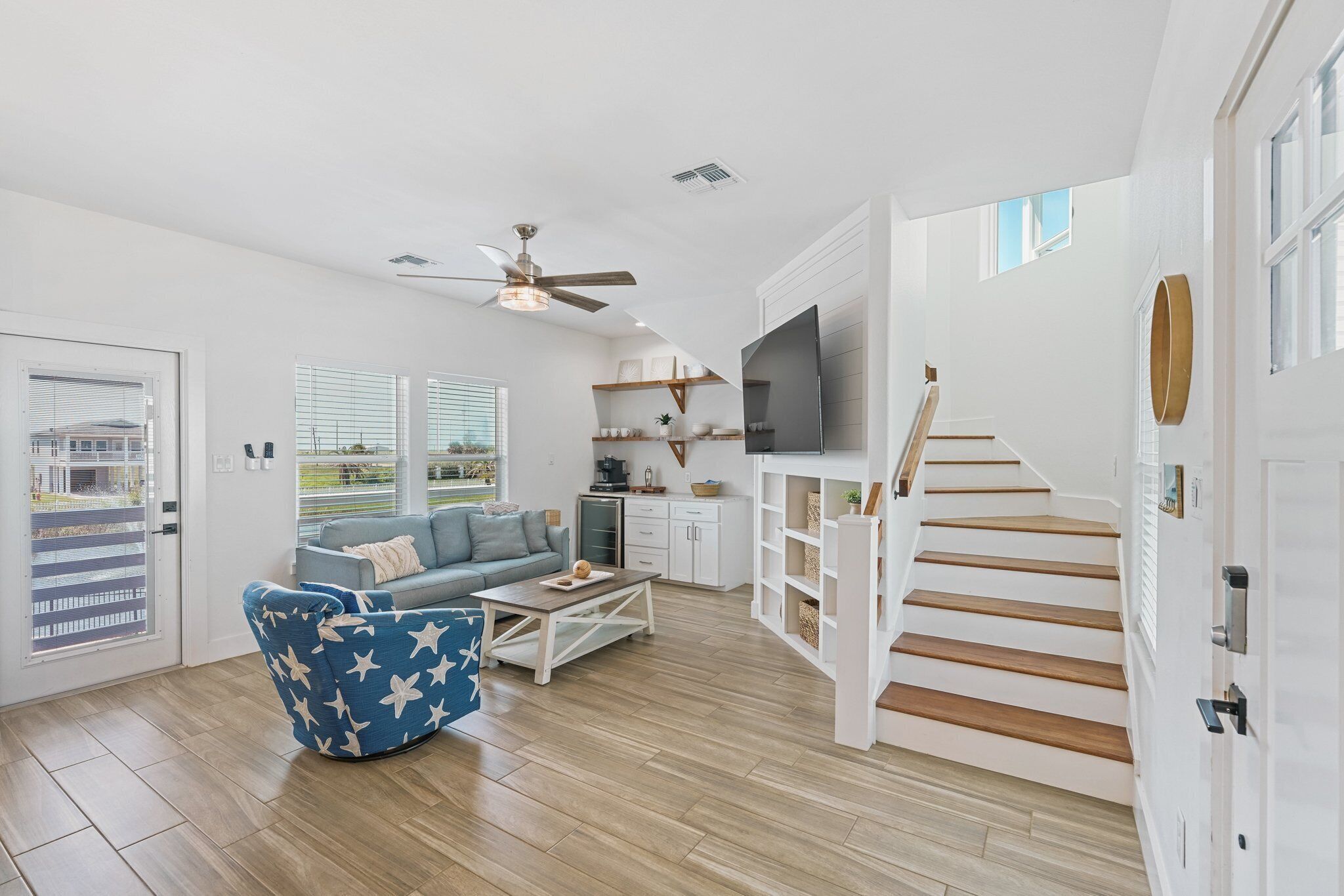A modern living room with a blue sofa, a coffee table, and a staircase leading to another level.