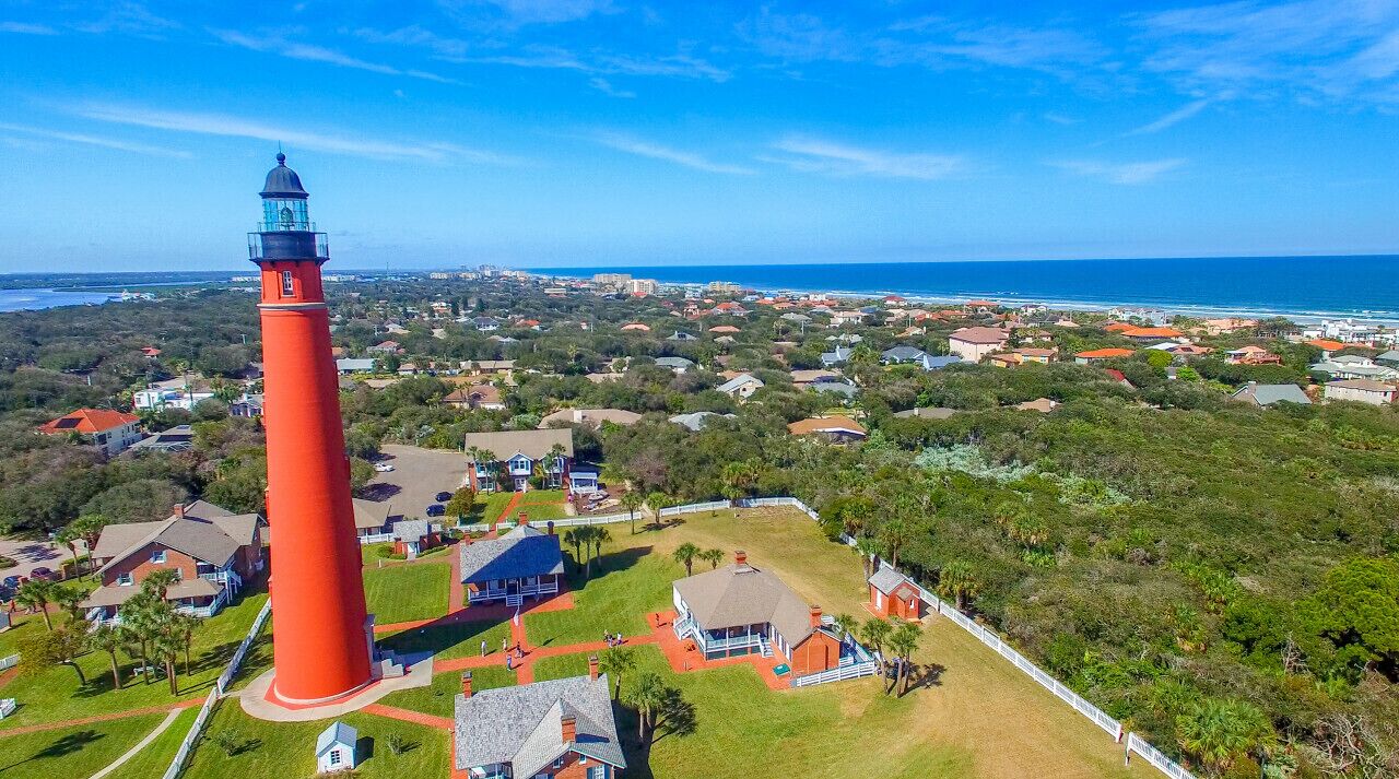 Un faro rojo con vistas despejadas a la zona residencial y al océano.
