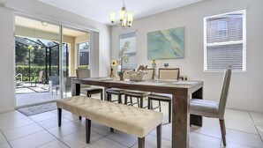 A dining area with a large table, multiple chairs, a bench, and a chandelier. - 6079-7-bo-enchanted Villa by Disney (Davenport)