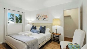A neatly arranged bedroom with a bed, bedside lamps, a chair, and a painting on the wall. - Marbella Lane Natural Bayview Escape Near SFO (Daly City)