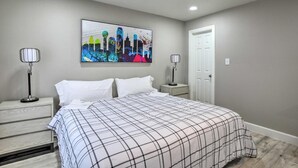 A bedroom with a bed, two bedside tables, a wall-mounted artwork, and a door. - Texas - Collins 3210 (Covington)