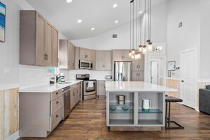 Una cocina moderna con armarios de madera, electrodomésticos de acero inoxidable y una isla central.