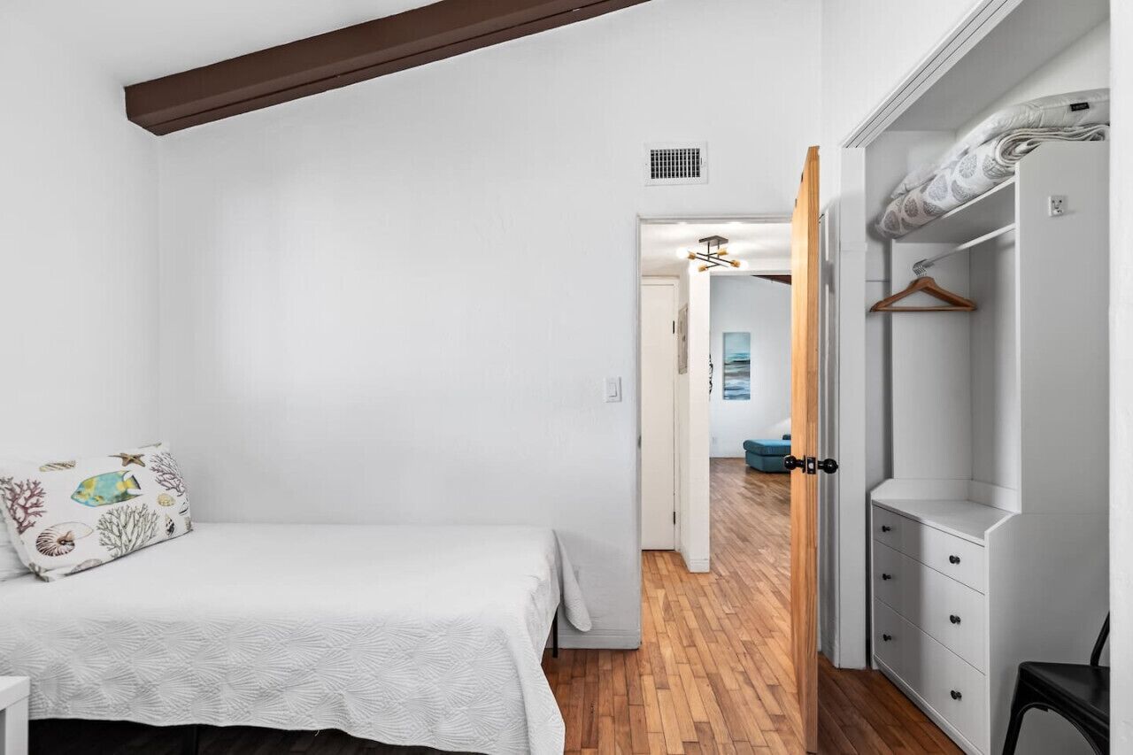 Een slaapkamer met een bed, een garderobe en een gang naar een andere kamer.