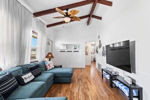 A living room with a sectional sofa, a ceiling fan, a flat-screen TV, and a wooden floor. - Summer Lovin' In Paradise (Daytona Beach)