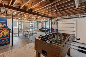 A spacious room with a foosball table, a ping pong table, and a dartboard. - Three Oars Beach Surf Shack Pool, Oceanview, Game Room (Daytona Beach)