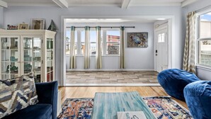 A living room with a sofa, a coffee table, a cabinet, and a view through a door to the outside. - Three Oars Beach Surf Shack Pool, Oceanview, Game Room (Daytona Beach)