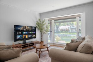 En stue med et fladskærms TV, et sofabord og to sofaer.