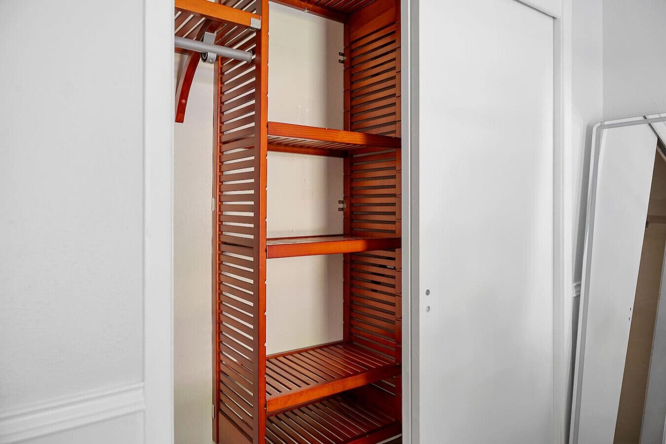 A walk-in closet with wooden shelves and a hanging rod.