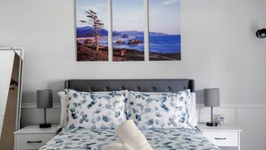 A bedroom with a bed, two bedside tables, a nightstand, and a wall-mounted lamp. - Play & Stay Dallas Home w/ Gym + Gameroom + Wifi (Dallas)