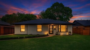 A modern two-story house with a well-maintained lawn, a garage, and a large tree in the background. - Play & Stay Dallas Home w/ Gym + Gameroom + Wifi (Dallas)