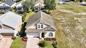 A residential house with a garage, a driveway, and a well-maintained lawn. - Famous Home in Davenport With Game Room (Davenport)