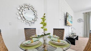 A dining area with a glass table, wicker chairs, and a decorative mirror on the wall. - Famous Home in Davenport With Game Room (Davenport)