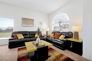 Ein modernes Wohnzimmer mit zwei schwarzen Ledersofas, einem Couchtisch und einem großen Fenster mit Blick auf Gebäude.