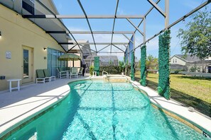 Ein Swimmingpool mit überdachtem Bereich, Liegestühlen und einem gläsernen Gewächshaus.