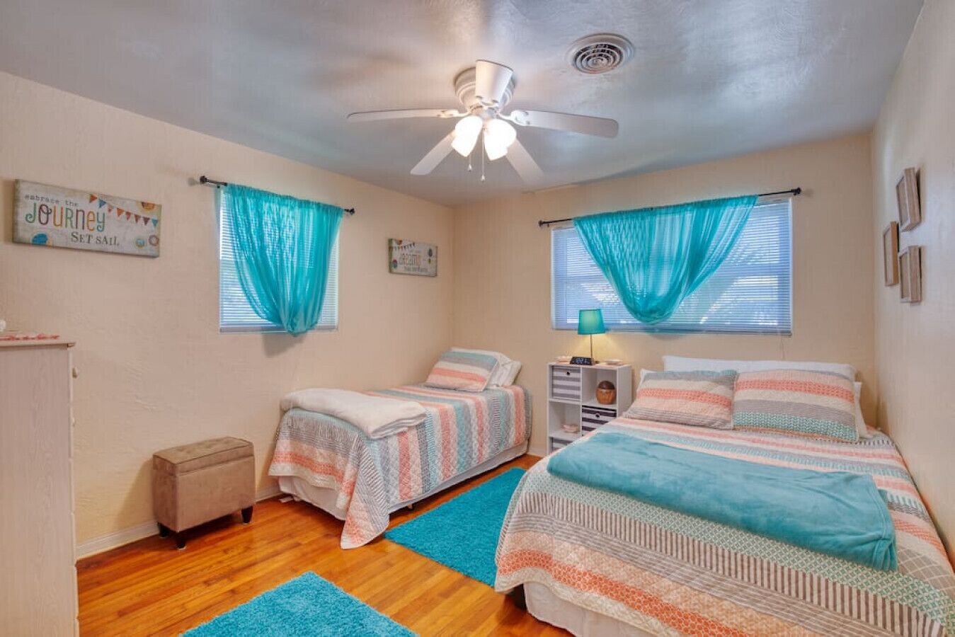 A bedroom with two beds, a ceiling fan, and a window with curtains.